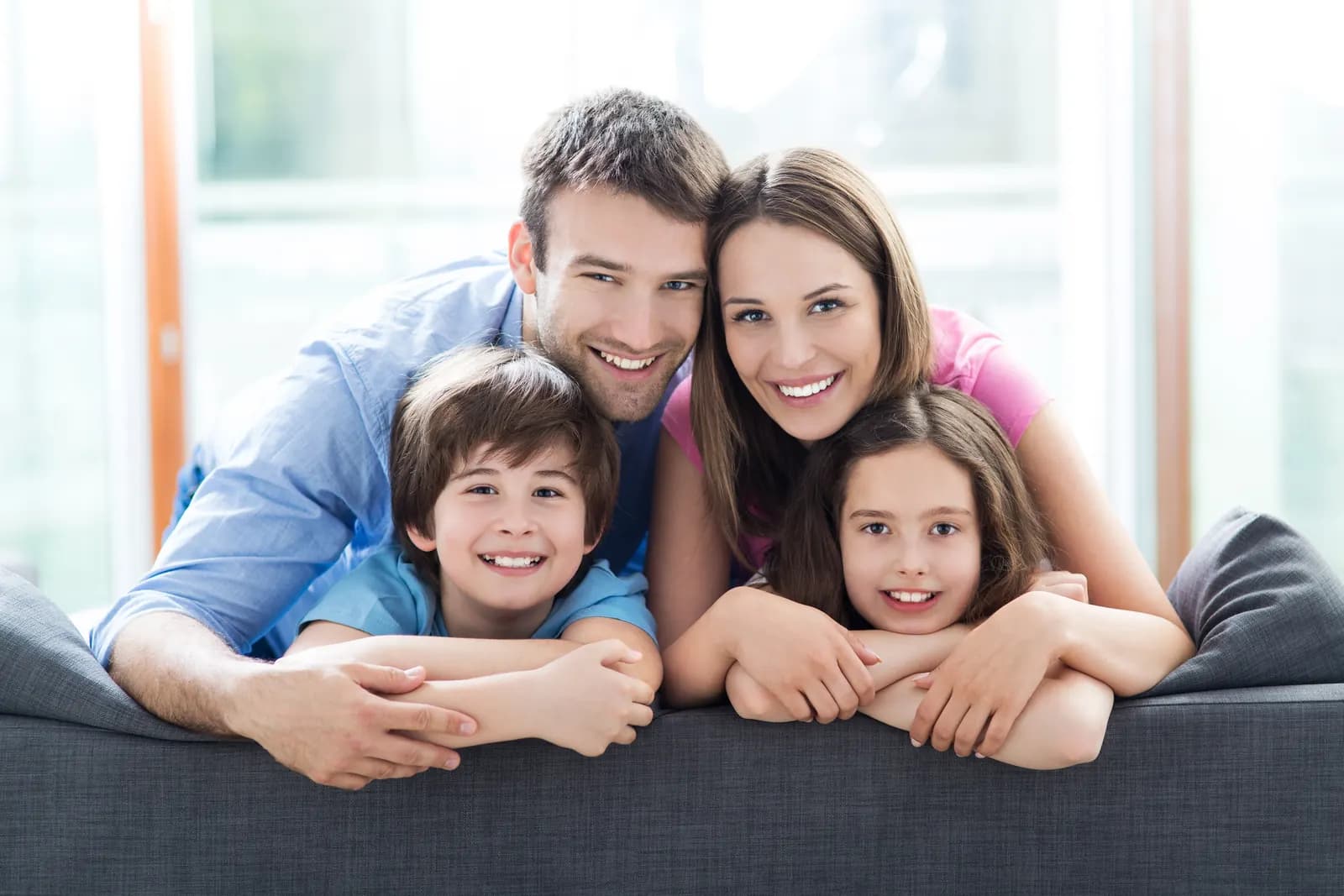 Family of four smiling together at home