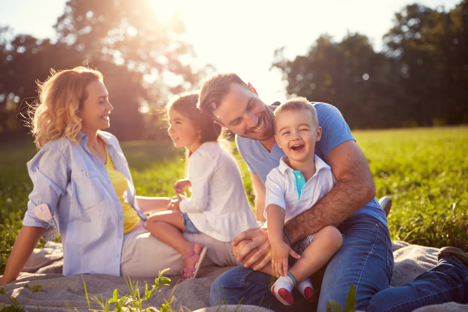 A family laughing together outdoors on a sunny day