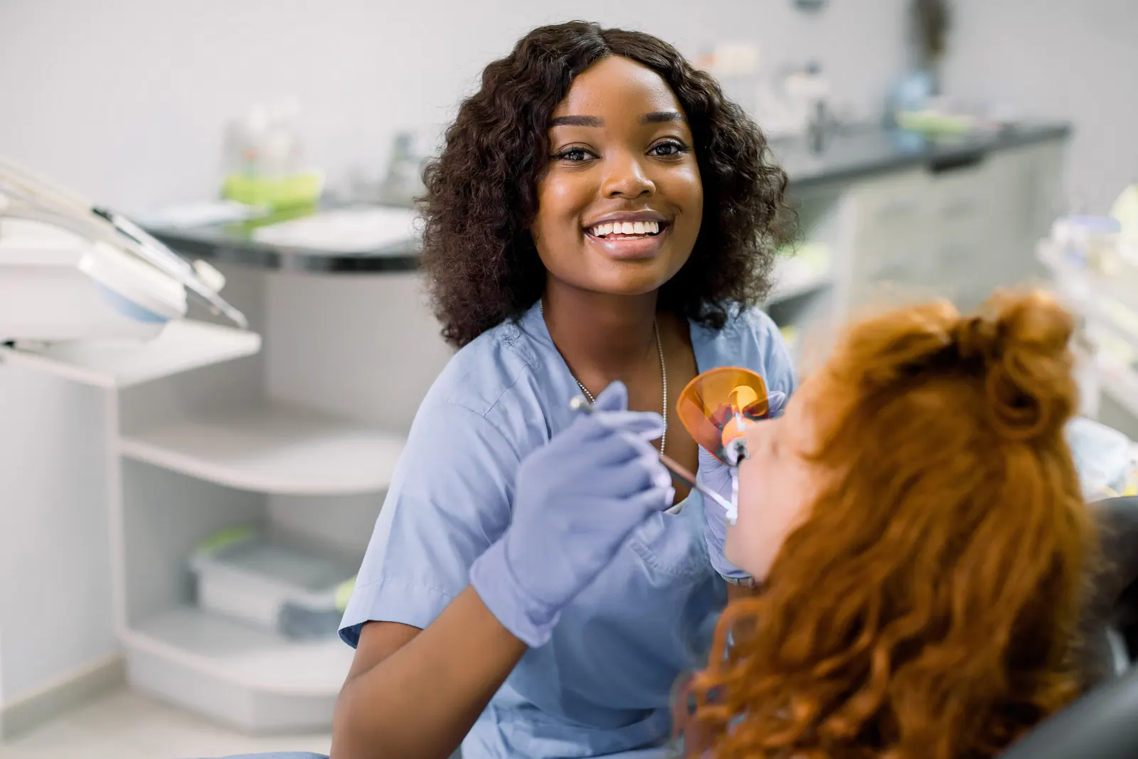 Dentist applying a cosmetic treatment to a smiling patient