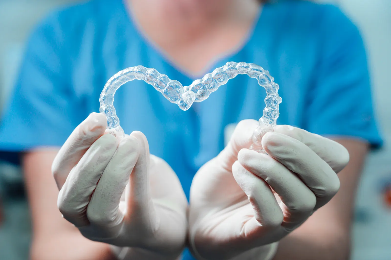 Two clear orthodontic aligners held to form a heart shape